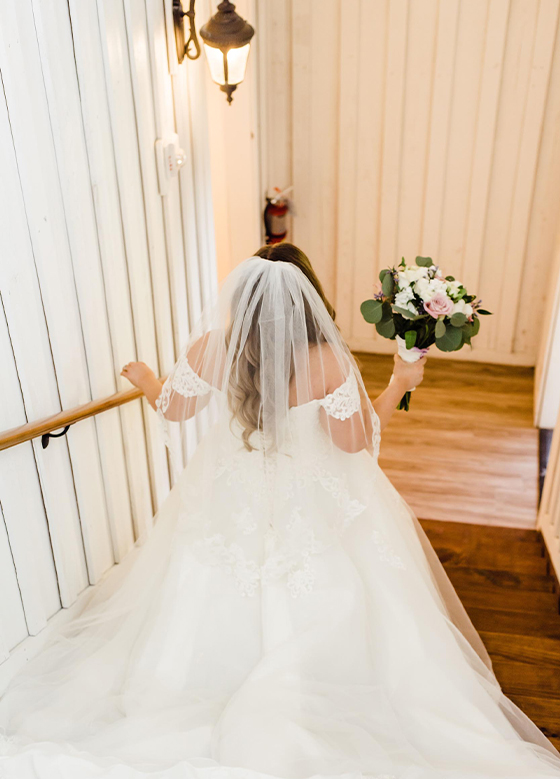 Bride Walking Down Wood Staircase to Reception Area