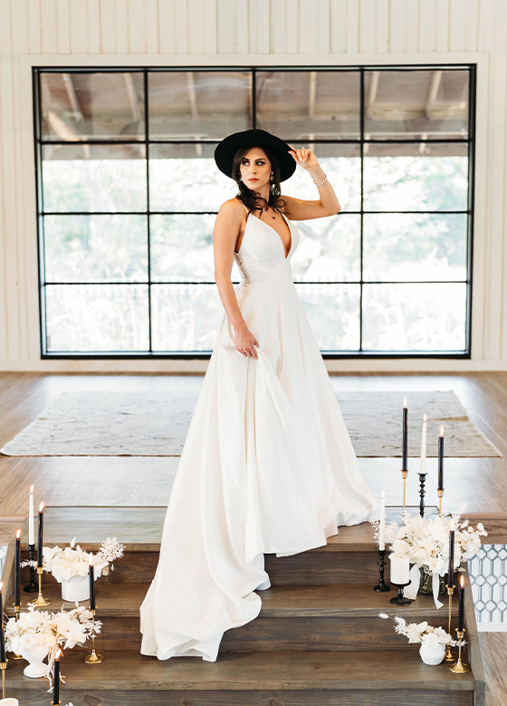 Bride Standing in Front of Black Framed Windows White Panel Walls Black Hat