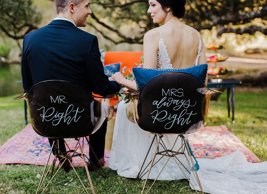 Bride and groom sitting on chairs with their names on them