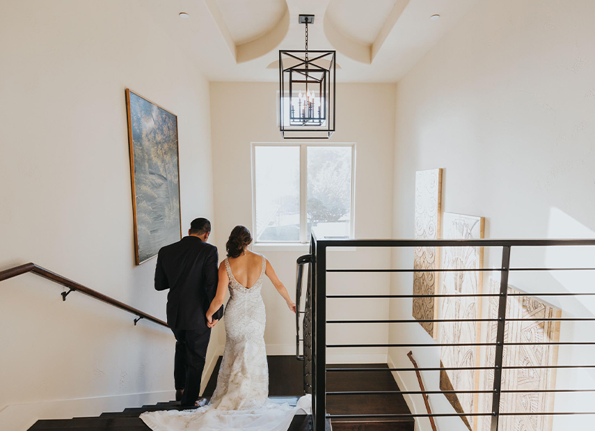 Bride and groom from behind walking down staircase
