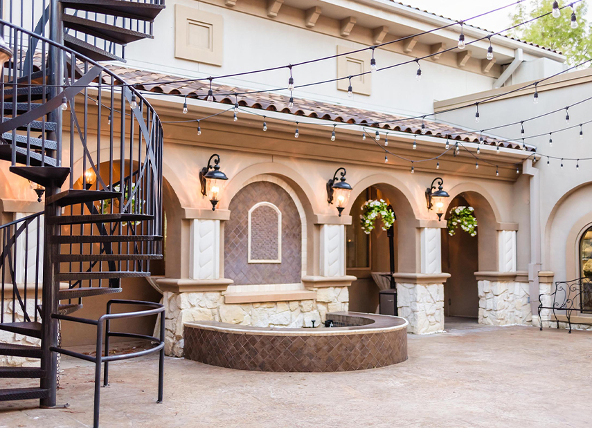 Tuscan-inspired courtyard with bistro lights and fountain