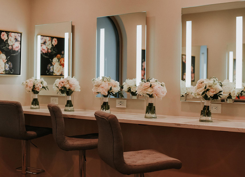 Salon-style getting ready suite with comfortable seating, flattering lighting and mirrors