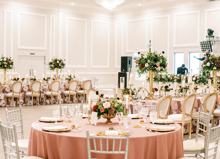Beautiful cream reception space with blush banquet tables and floral arrangements