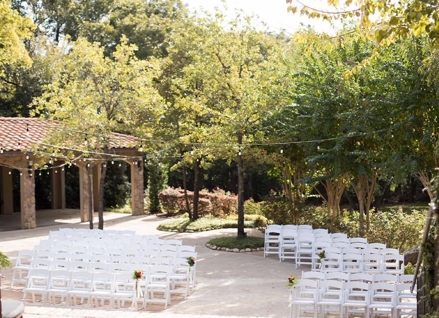Outdoor ceremony set up in Tuscan-style courtyard surrounded by trees