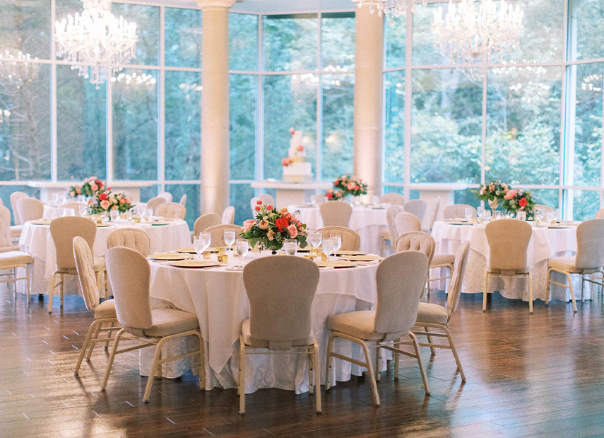 Beautiful ivory reception set up with banquet tables, velvet chairs, and chandeliers