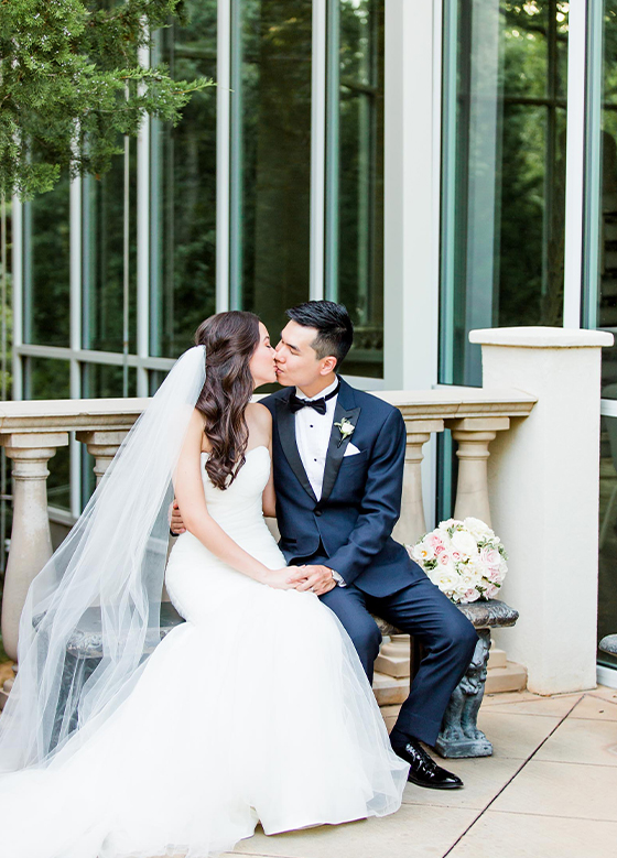 Bride and groom kissing outside in front of reception space windows
