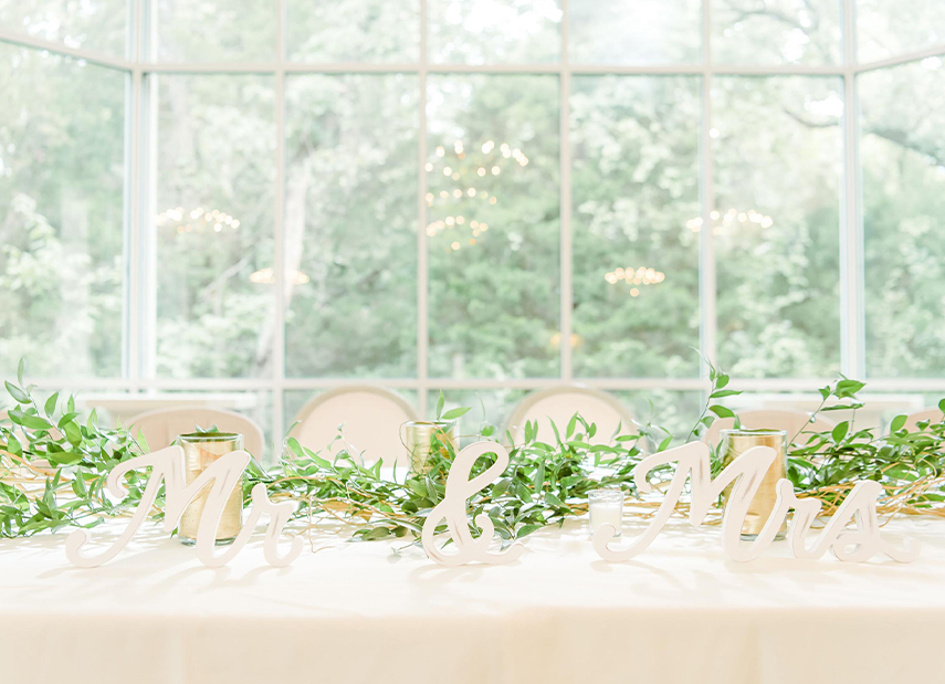 Close up of sweetheart table in front of floor to ceiling windows with forest views