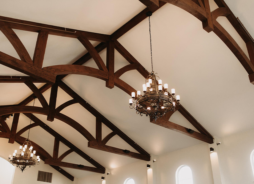 View of white chapel ceiling with dark wood accents and gorgeous chandeliers