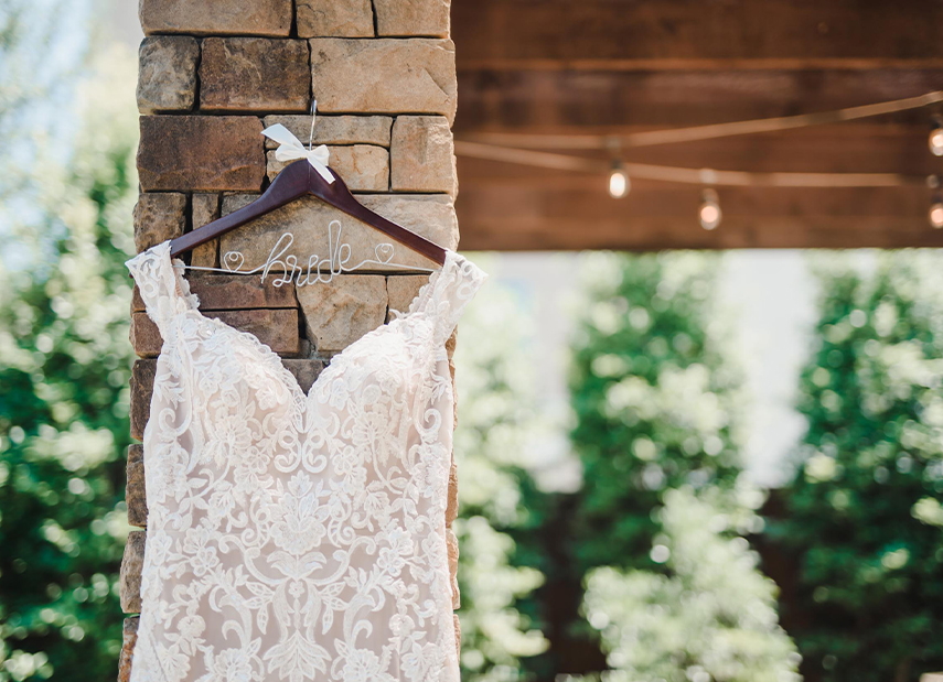 Close up of bridal gown hanging on brick pillar