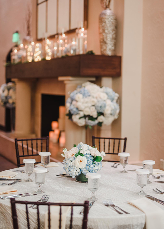 Close up of round banquet table set up with blue and white florals and white china