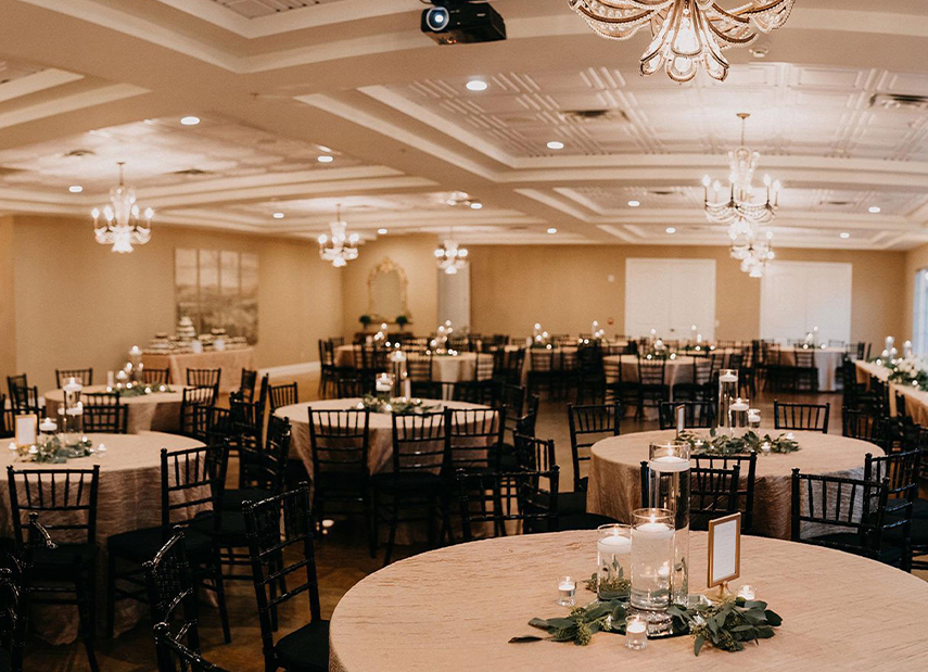 Elegant tan reception space with white detailed ceilings and chandeliers