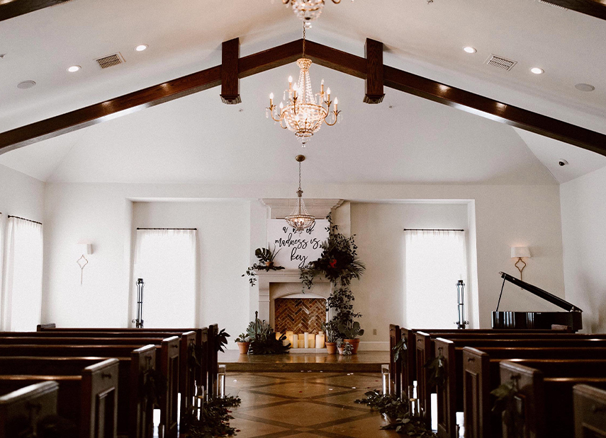 View down aisle of white modern chapel with dark brown wood accents and fireplace