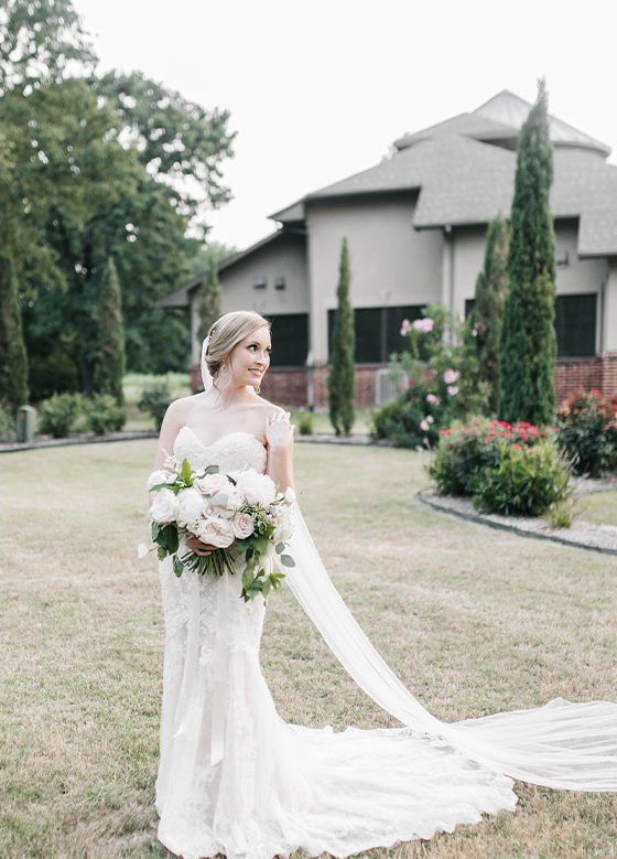 Bride outside with white bouquet, aristide flower mound in background