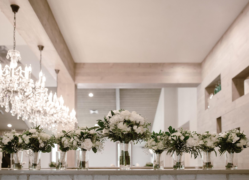 View of bouquets lined up in vases with chandeliers in the background