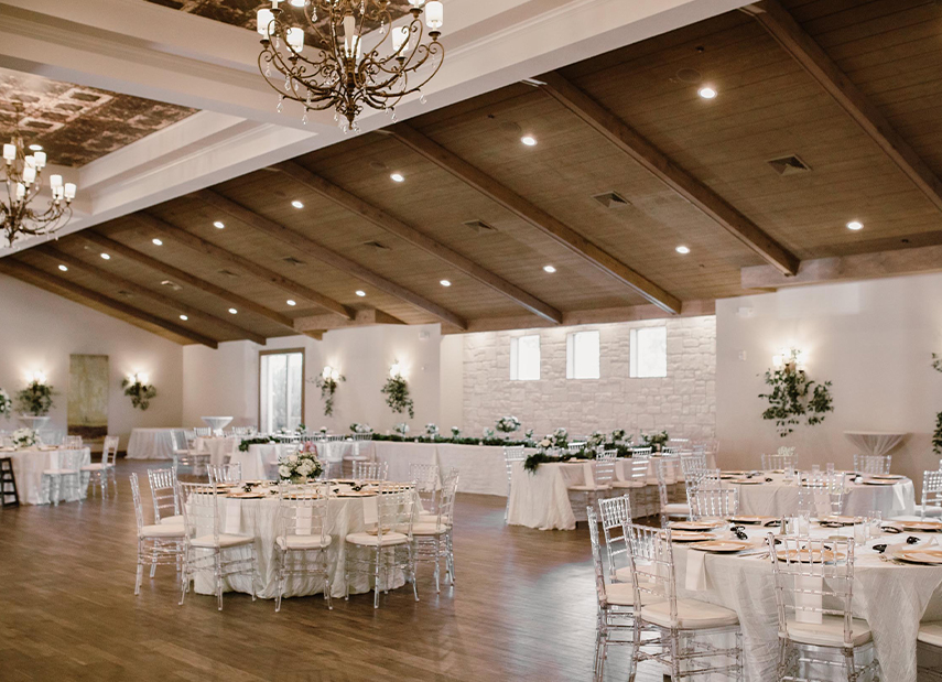 Ballroom with white tables set up, tin ceilings and modern chandeliers