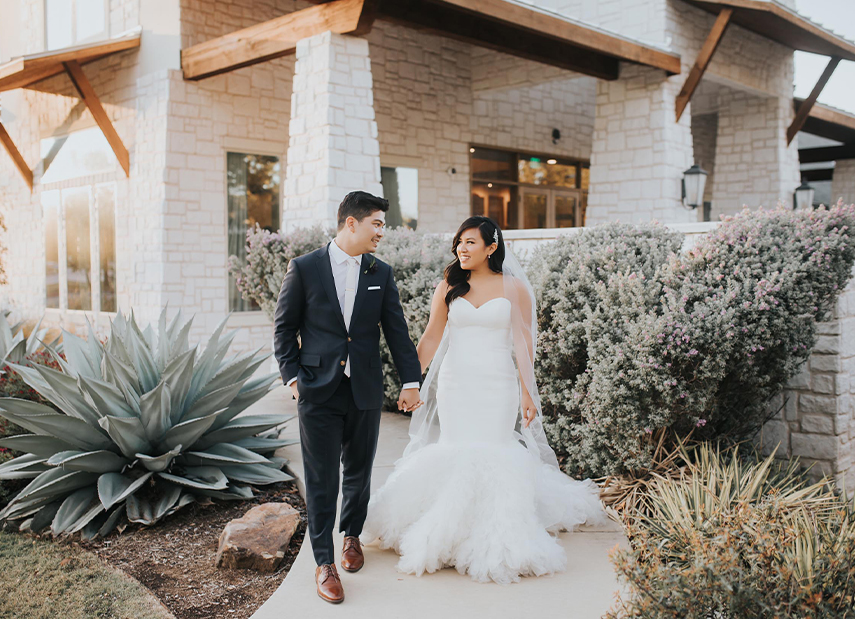 Bride and groom walking outdoor pathway flanked by dessert botanicals
