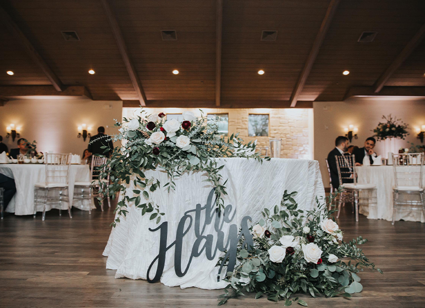 Sweetheart table with custom monogram and florals in white and green