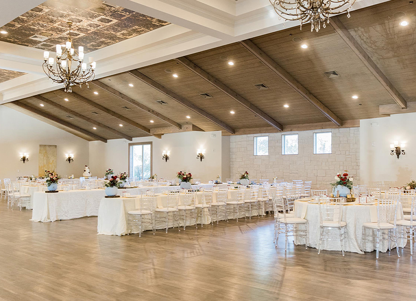 Ballroom with white tables set up, taupe ceilings and modern chandeliers