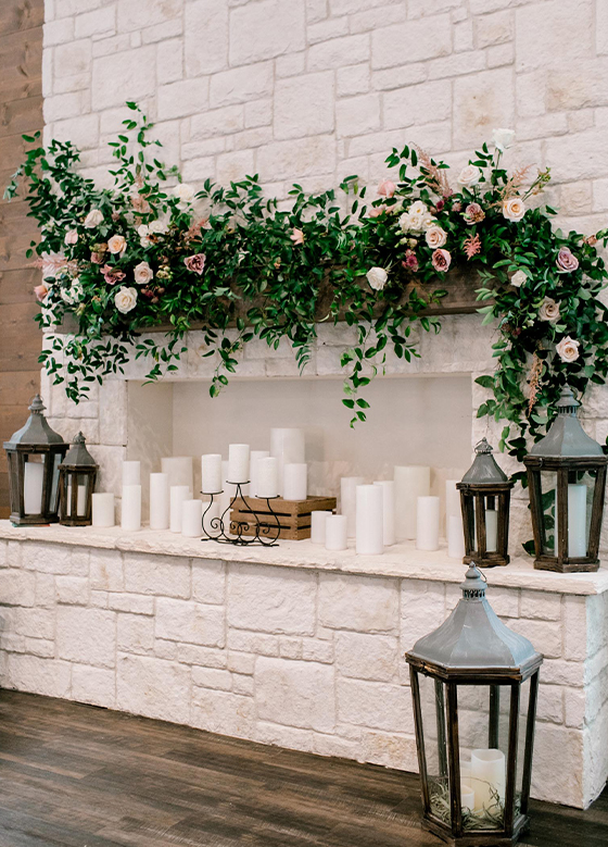 Close up of modern stone fireplace with metal lanterns and florals and greenery on mantle