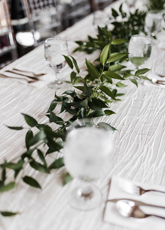 Close up of table with white linen and greenery runner