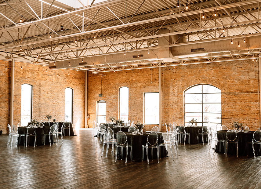View of industrial ballroom with round banquet tables with charcoal grey linens