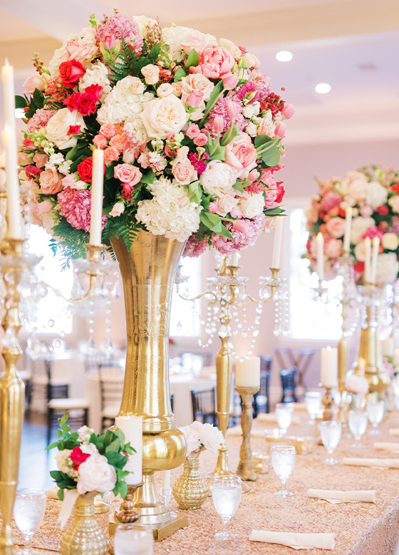 Close up of table set with gold pillar centerpieces with pink and white florals
