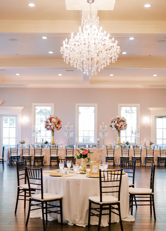 Ballroom with round tables with white linens and grand chandeliers