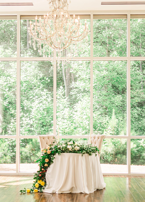sweetheart table and chandelier with floor to ceiling windows