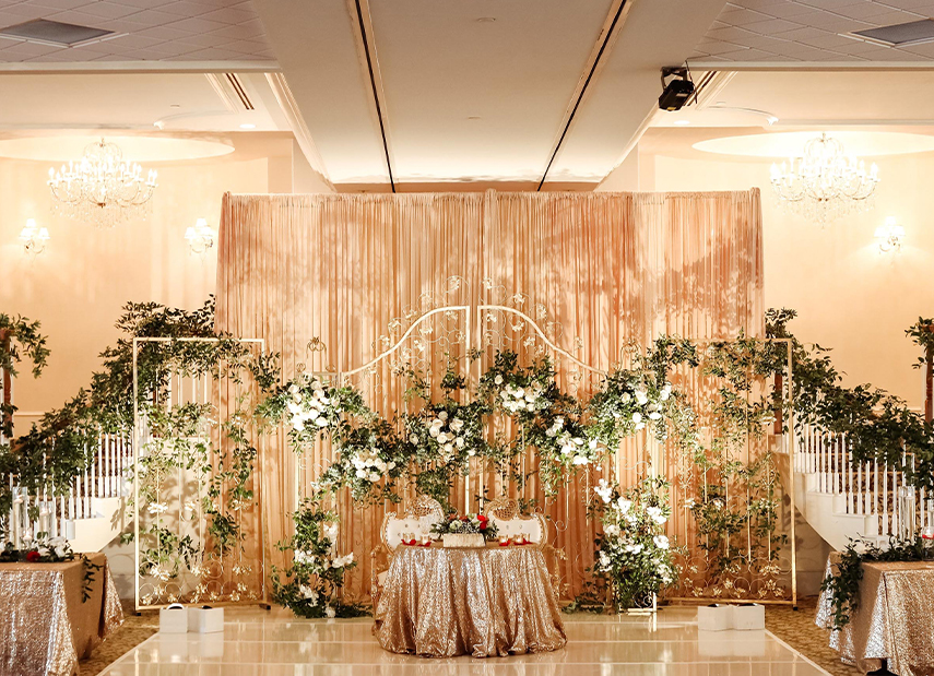 Sweetheart table with good tablecloths in front of floral backdrop