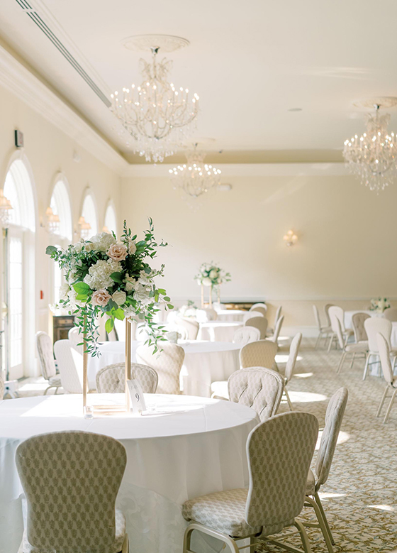 Sunlit wedding reception space filled with round white tables