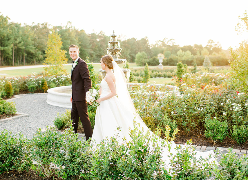 Bride and groom walking through gardens