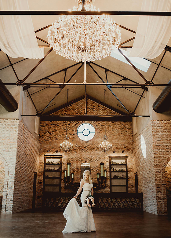 Bride looking down inside of room with high ceilings and chandelier