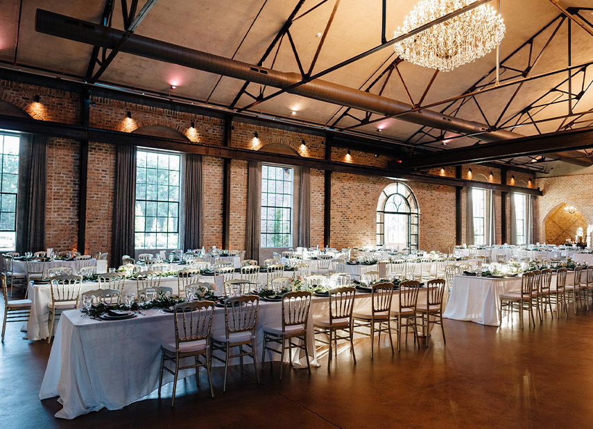 Long wedding reception tables with chandeliers hanging above