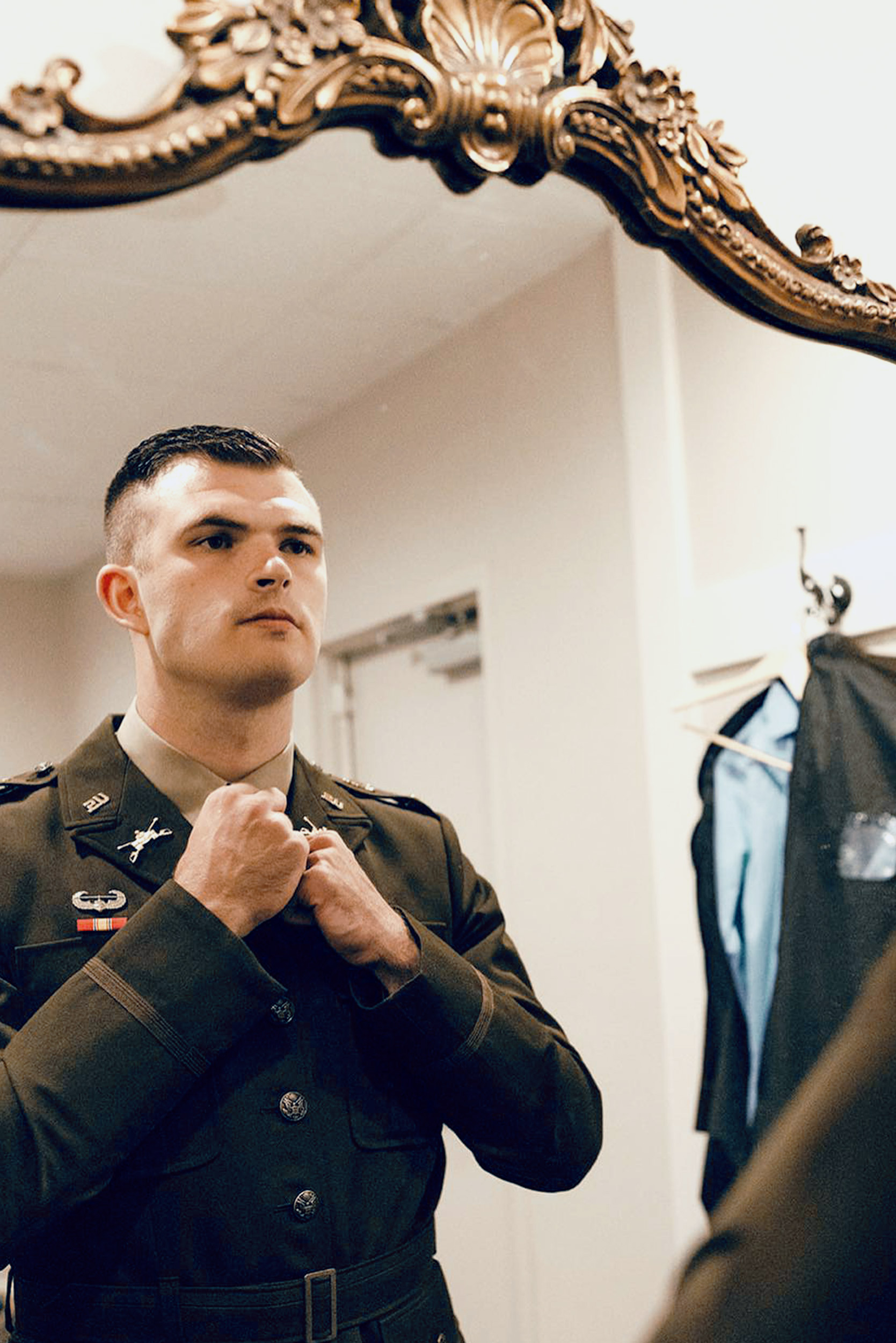 Groom in military uniform fixing tie in mirror