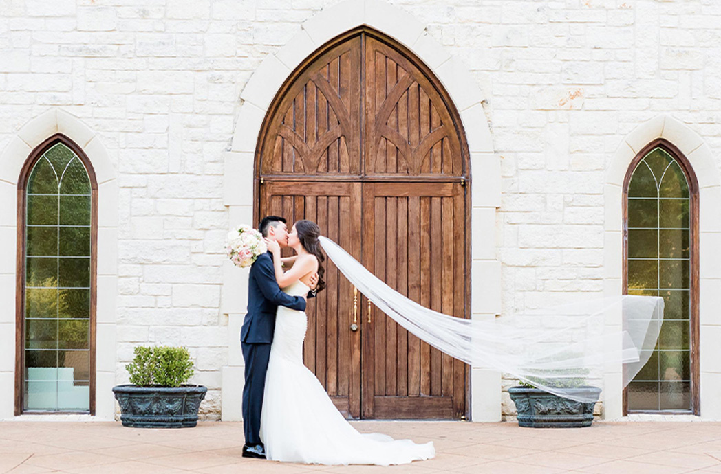 Bride and groom kissing in front of wooden chapel door
