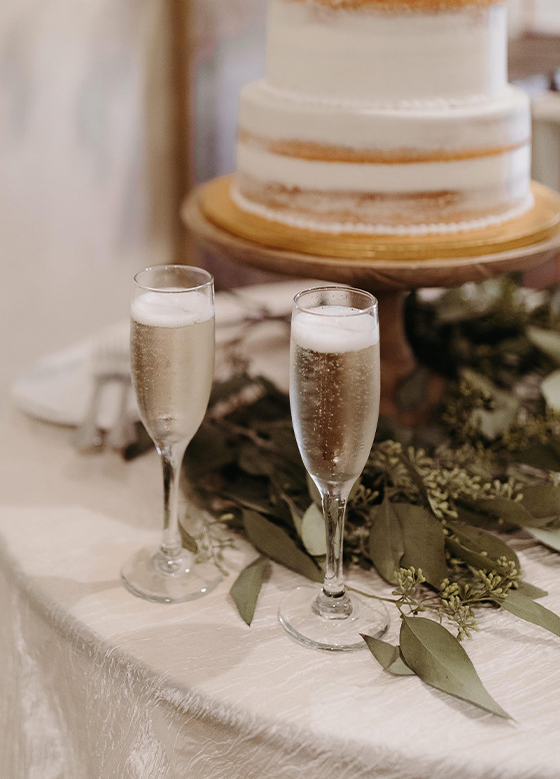 Champagne flutes in front of naked cake
