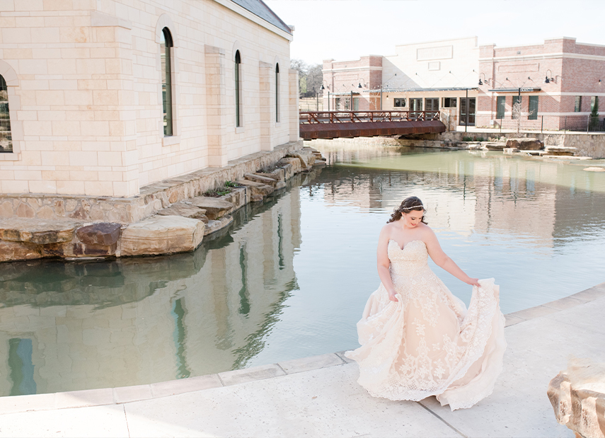 Bride Holds Dress Smiling Waterfront Exterior View Chapel at Riverwalk Flower Mound