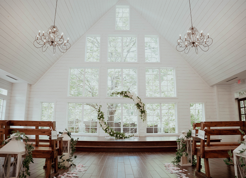 Chapel Ceremony Arbor Greenery White Feathers Chandeliers Clean White Panel Walls